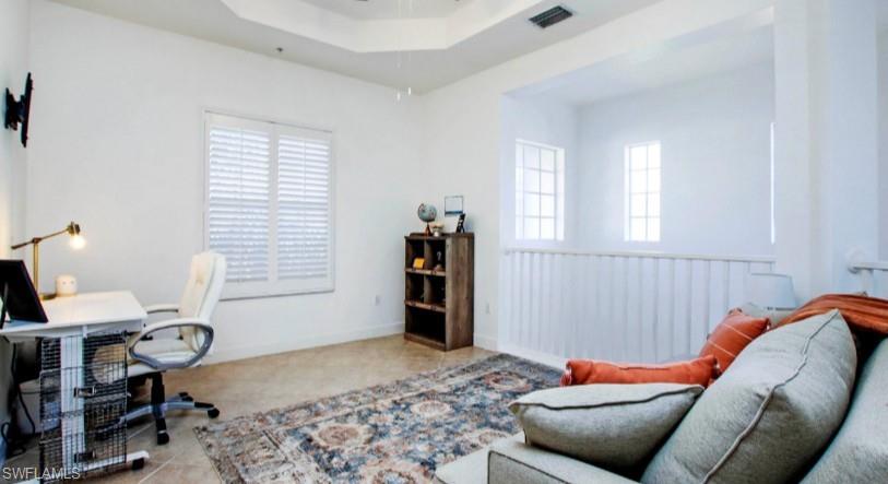 Office space with a tray ceiling and baseboards