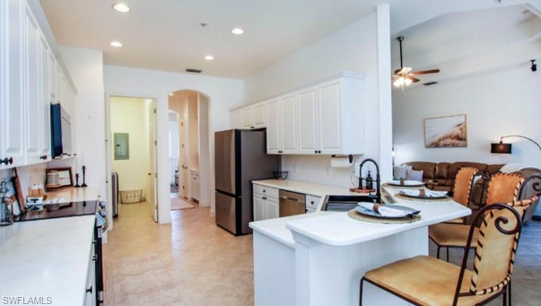 Kitchen featuring light countertops, arched walkways, a peninsula, stainless steel appliances, and white cabinetry