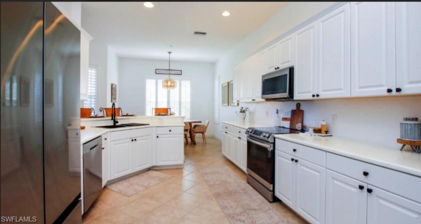 Kitchen with stainless steel appliances, light countertops, and white cabinetry