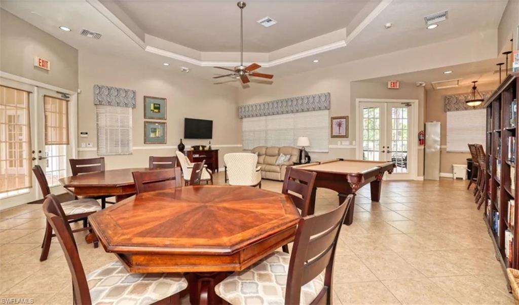 Dining area with french doors, a tray ceiling, billiards, ceiling fan, and light tile patterned floors