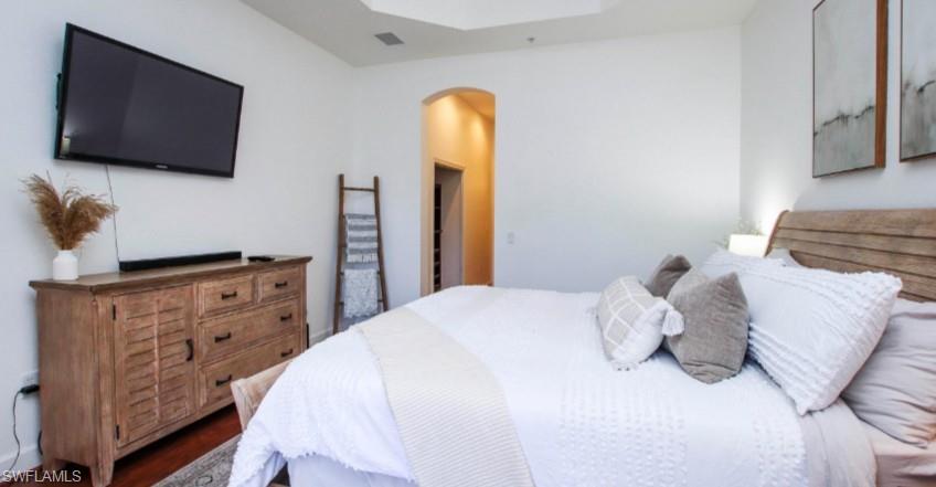 Bedroom with arched walkways and dark wood-style flooring