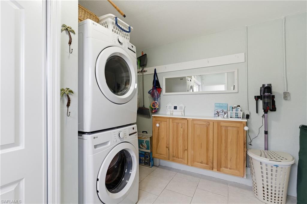 Laundry room featuring stacked washer and clothes dryer and light tile patterned floors