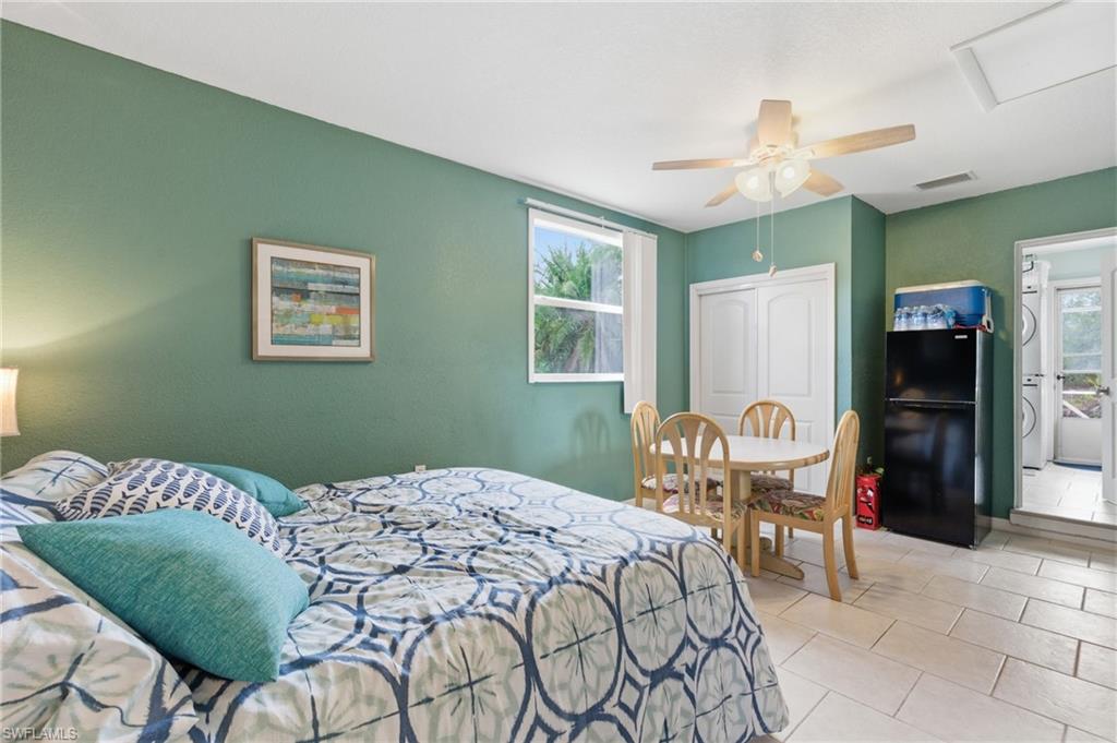 Bedroom featuring freestanding refrigerator, a closet, multiple windows, and ceiling fan