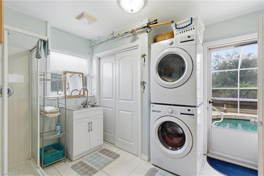 Laundry area with stacked washer / dryer and light tile patterned floors