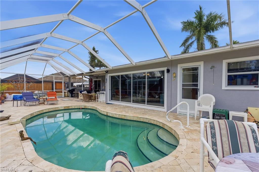 Swimming pool featuring a sunroom, a patio area, and glass enclosure