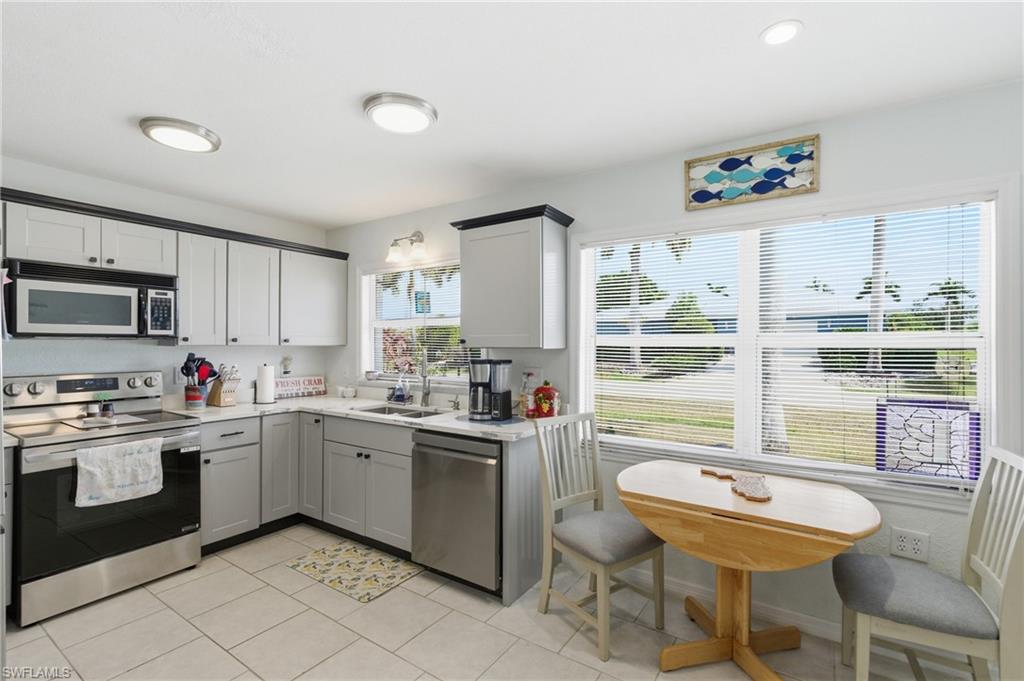 Kitchen featuring stainless steel appliances, light tile patterned floors, and two tone color scheme