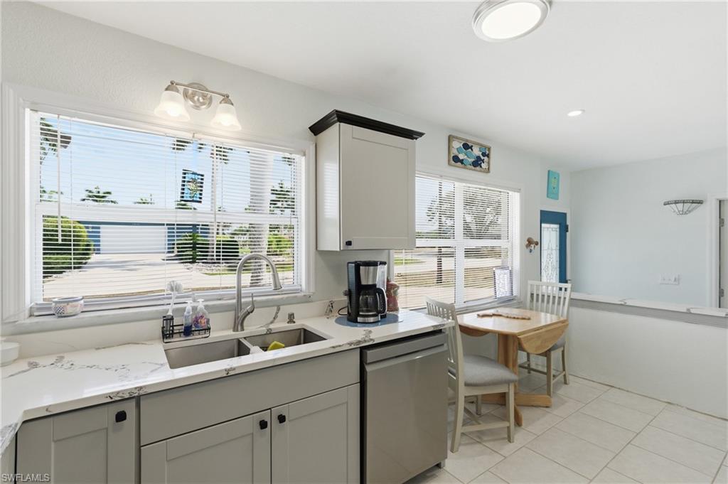 Kitchen featuring dishwasher, light stone counters, and healthy amount of natural light