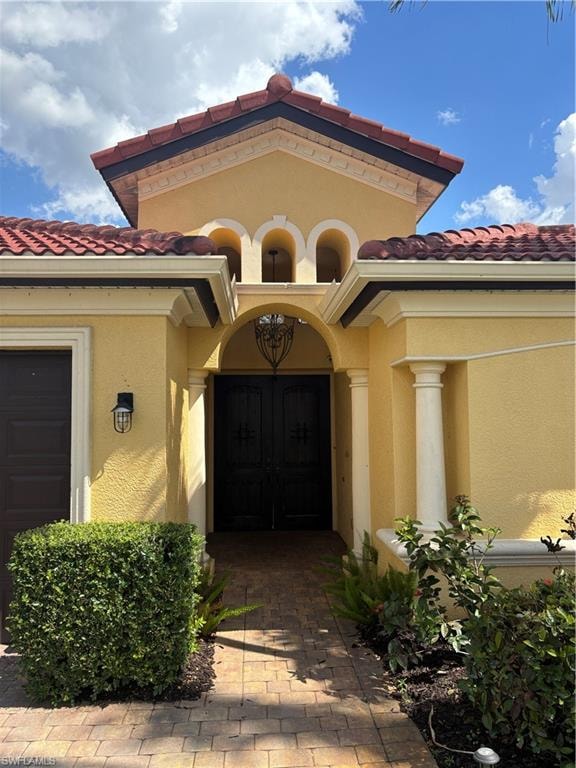 Entrance to property with a tiled roof and stucco siding
