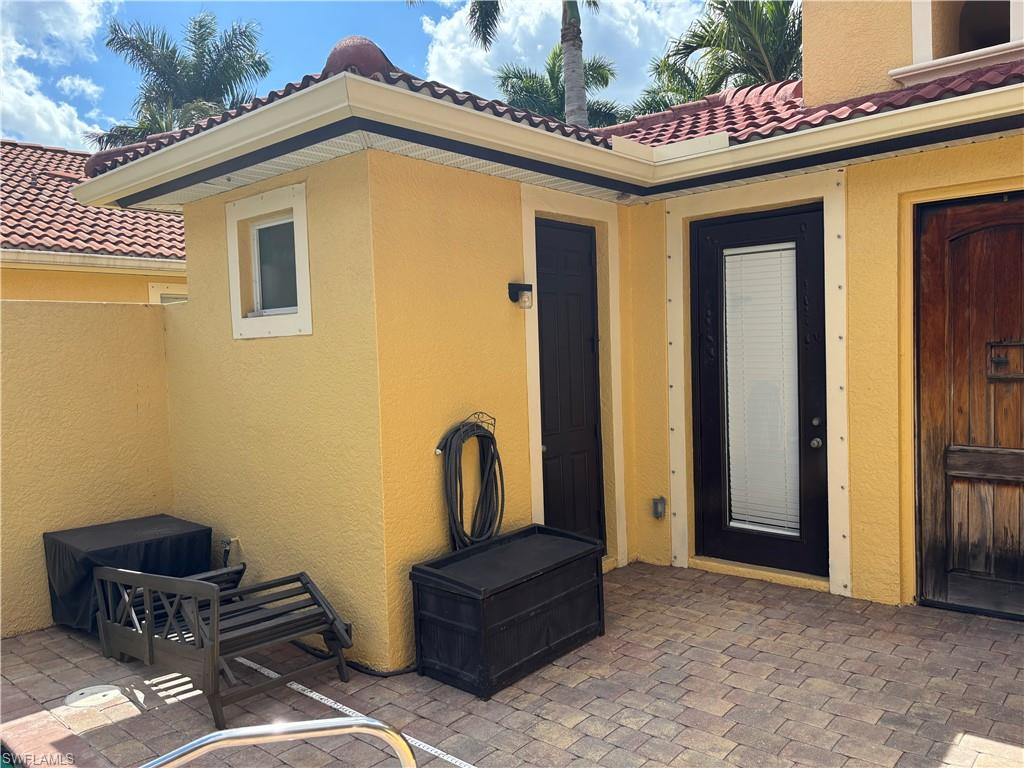 Doorway to property with a tiled roof, a patio, and stucco siding
