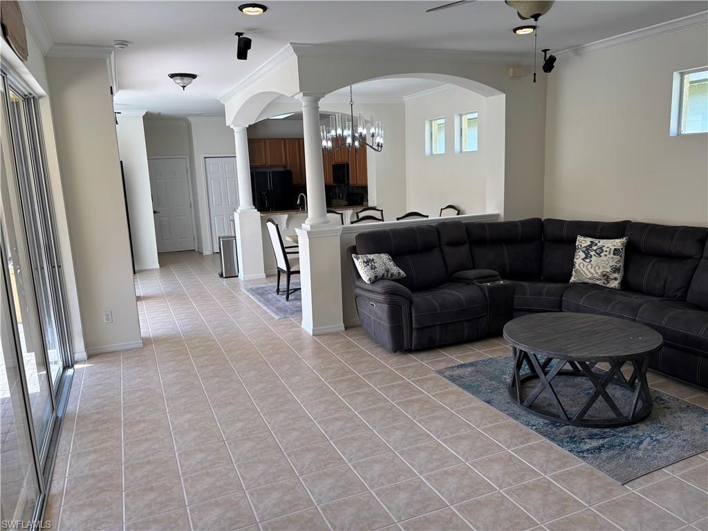 Living room featuring ornamental molding, a chandelier, light tile patterned floors, and arched walkways