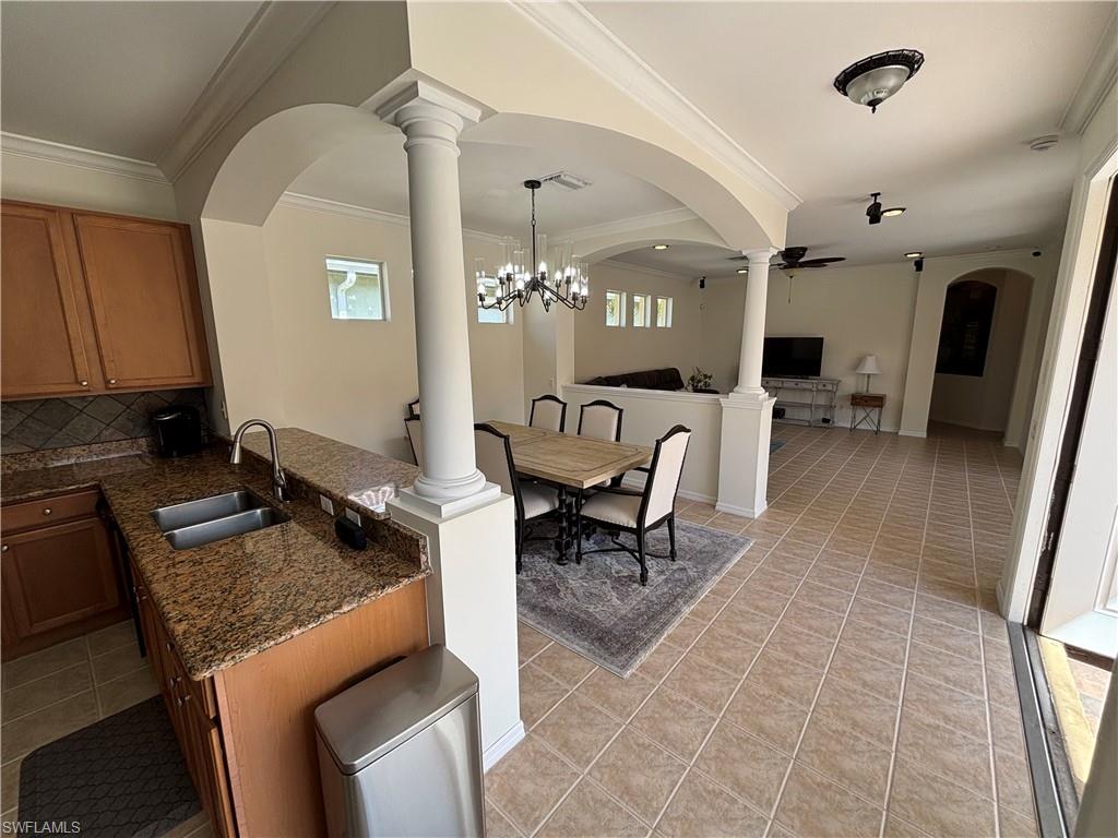 Kitchen with open floor plan, dark stone counters, wood finish cabinets, crown molding, and tasteful backsplash