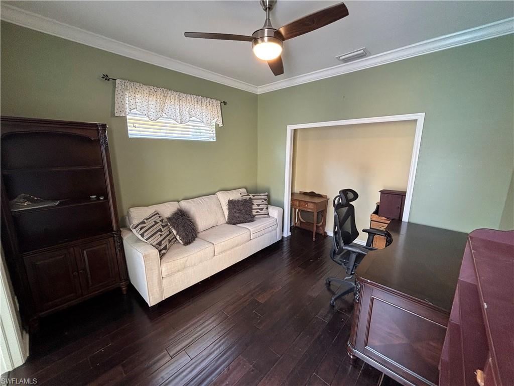Office space featuring crown molding, dark wood-style flooring, and ceiling fan