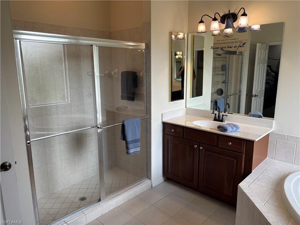 Full bathroom featuring vanity, a shower stall, light tile patterned floors, and a bath