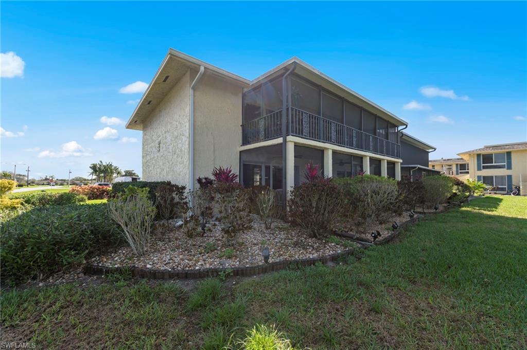 Rear view of property with a sunroom, a lawn, and a balcony