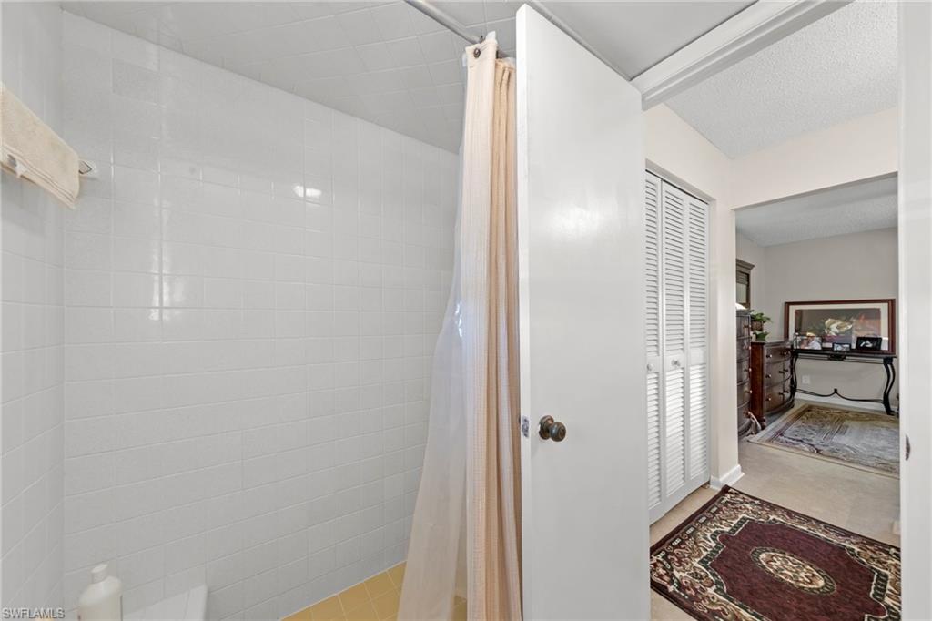 Bathroom featuring a shower stall, a closet, and a textured ceiling