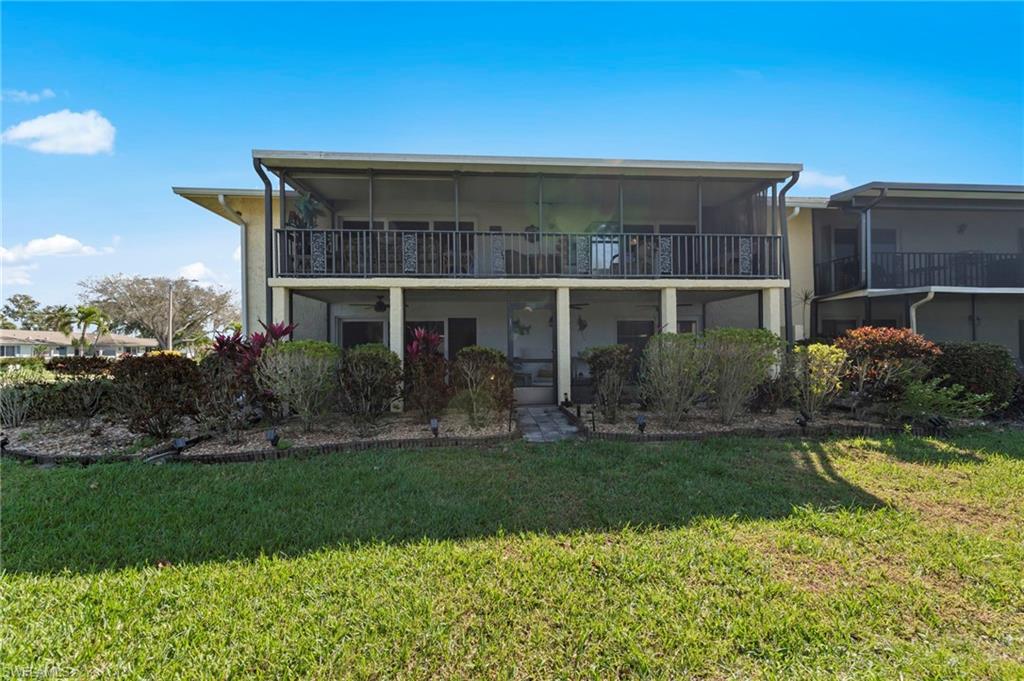 Rear view of property with a yard, a sunroom, and a balcony