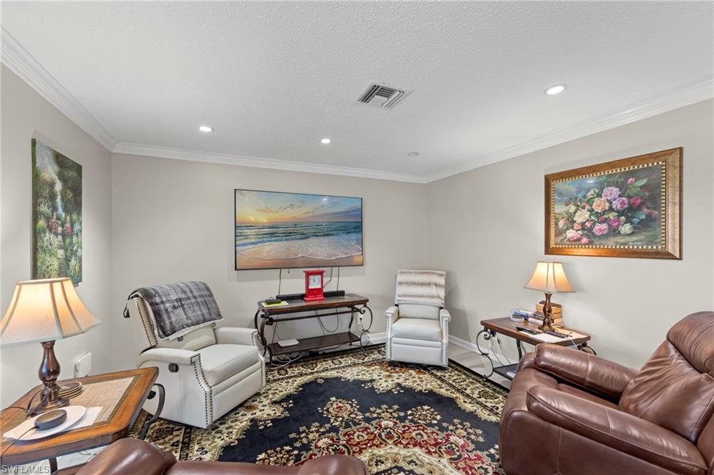 Living room with ornamental molding, recessed lighting, and a textured ceiling