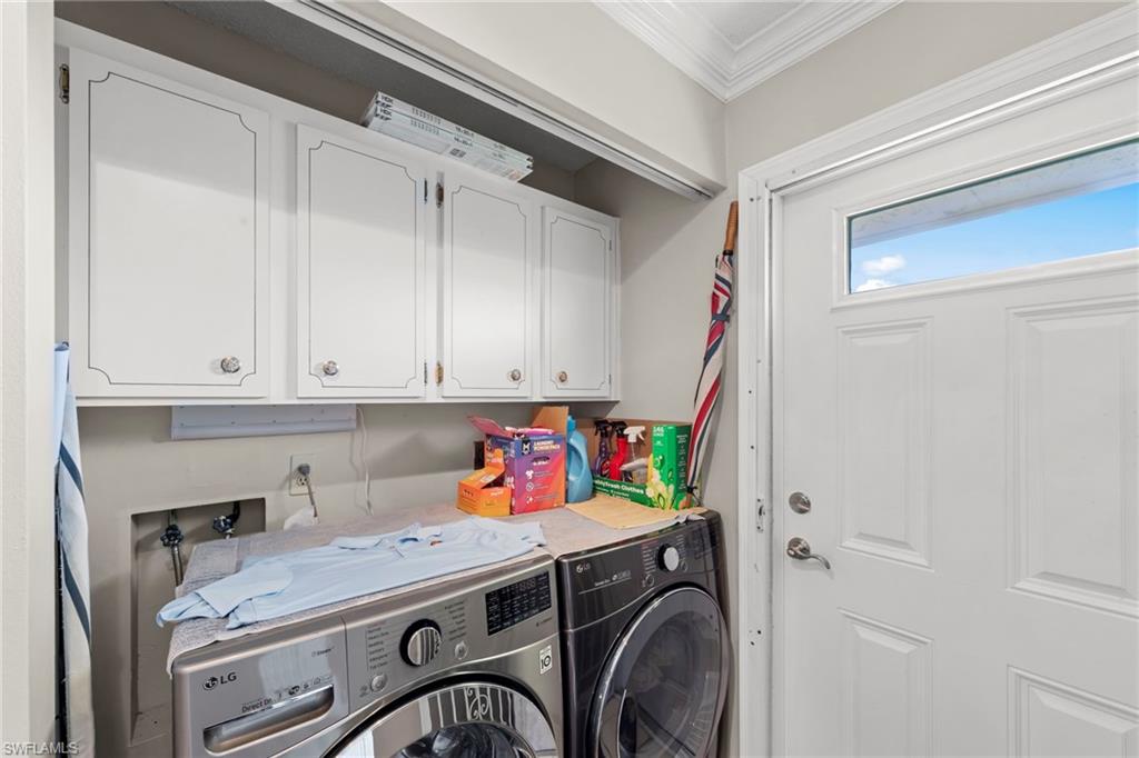 Laundry area featuring cabinet space, independent washer and dryer, and ornamental molding