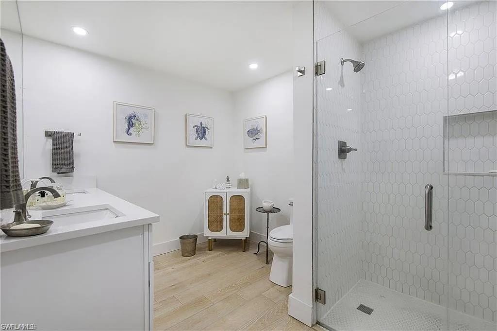 Bathroom featuring double vanity, light wood finished floors, a stall shower, and recessed lighting