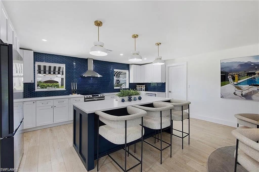 Kitchen featuring a breakfast bar, light wood-type flooring, freestanding refrigerator, a center island, and backsplash