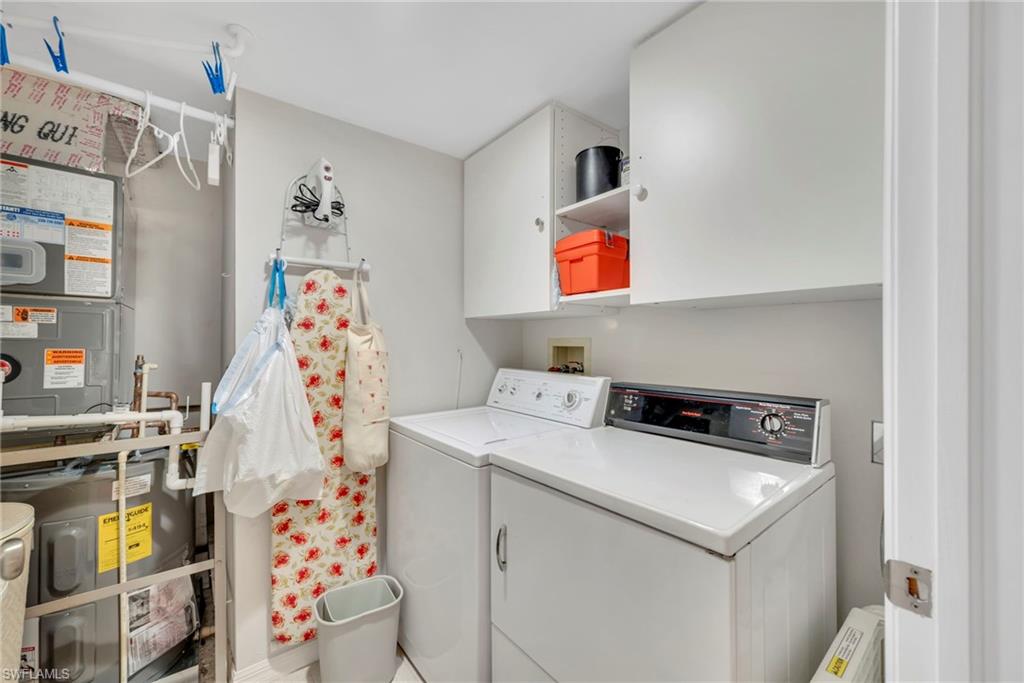 Laundry area featuring cabinet space, independent washer and dryer, and water heater & AC