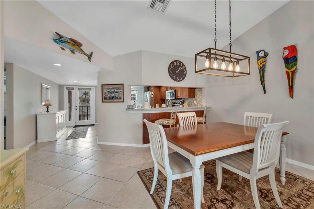 Dining area with light tile patterned floors, vaulted ceiling, and recessed lighting