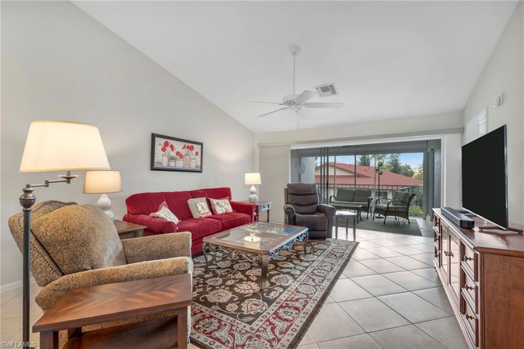 Living area featuring vaulted ceiling, a ceiling fan, and light tile patterned floors