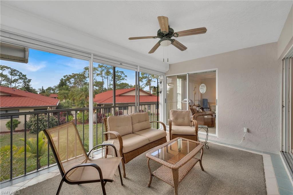 Sunroom featuring a textured wall, a ceiling fan, tile patterned flooring, and an outdoor lounge area