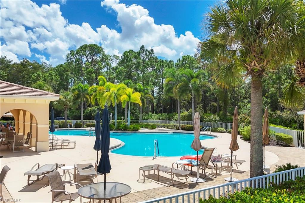 Community pool featuring a patio, view of scattered trees, and a gazebo