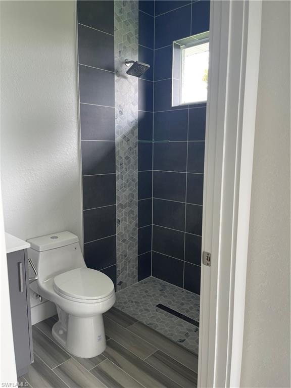 Full bath featuring a shower stall, vanity, a textured wall, and wood finish floors