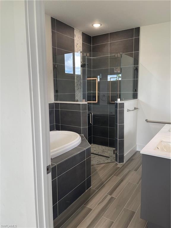Bathroom with vanity, wood finish floors, a shower stall, and a garden tub