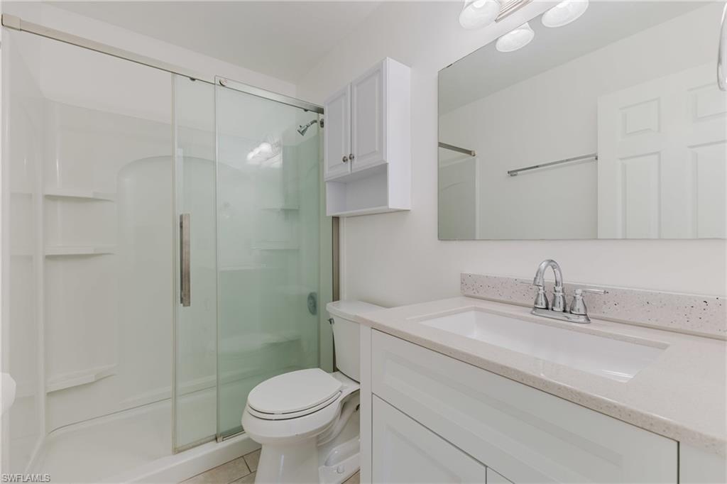 Full bathroom with vanity, a stall shower, and light tile patterned flooring