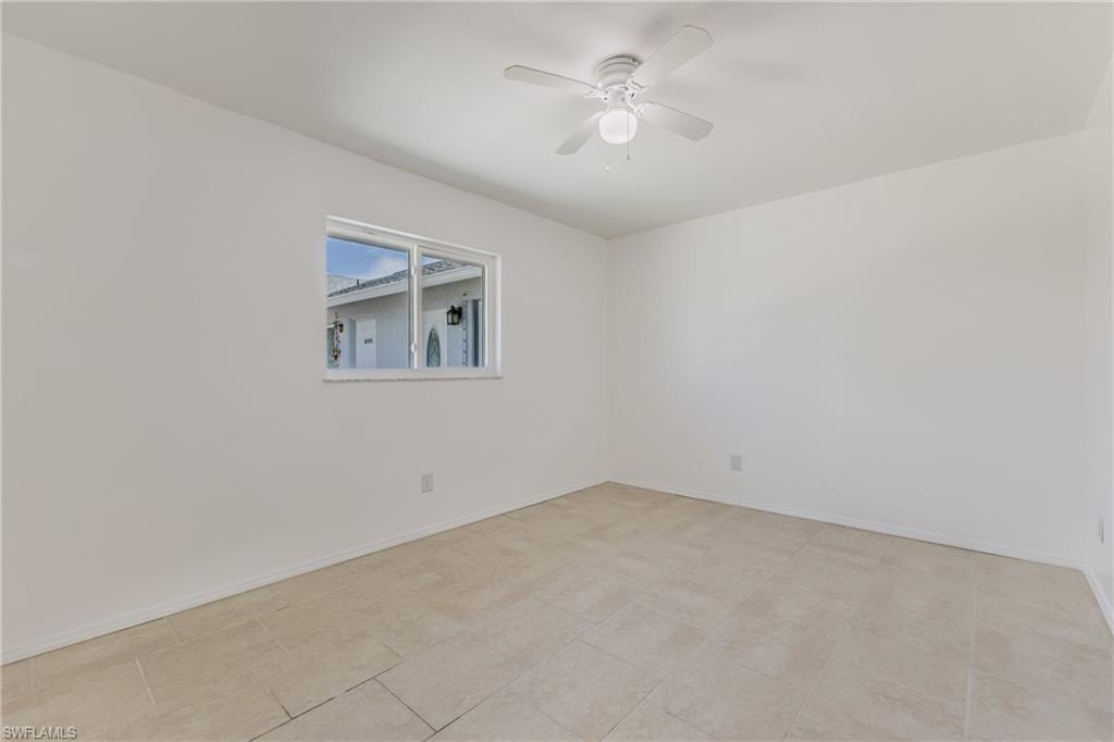 Empty room featuring ceiling fan and baseboards
