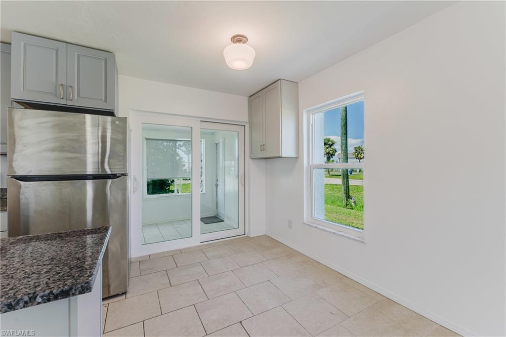 Kitchen featuring freestanding refrigerator, gray cabinetry, dark stone counters, and light tile patterned flooring