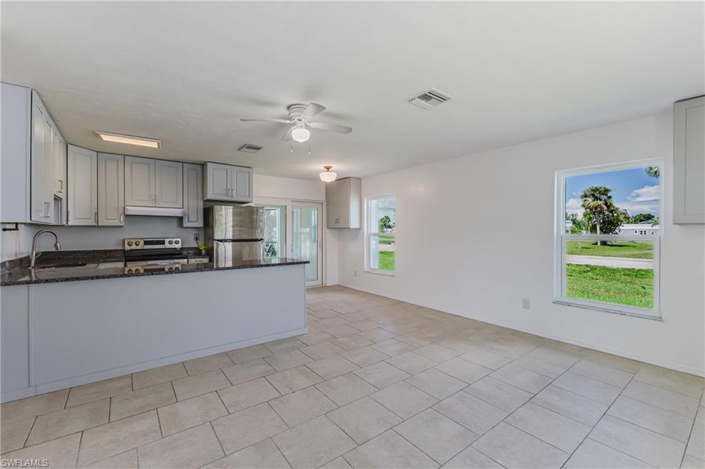 Kitchen featuring dark stone counters, ceiling fan, a peninsula, stainless steel appliances, and gray cabinets