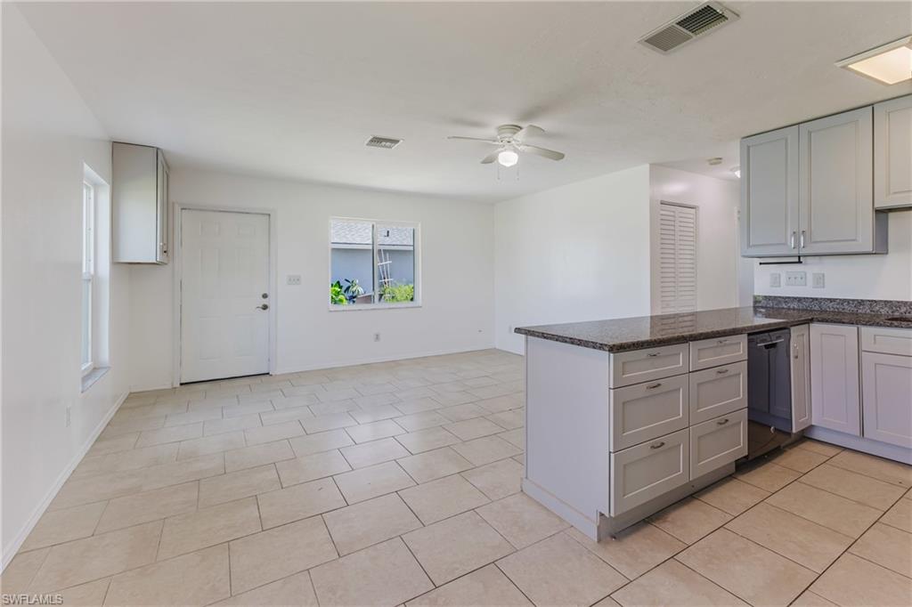 Kitchen with ceiling fan, dark stone countertops, a peninsula, dishwasher, and light tile patterned flooring