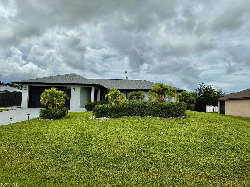 Ranch-style house featuring concrete driveway, a front lawn, an attached garage, and stucco siding