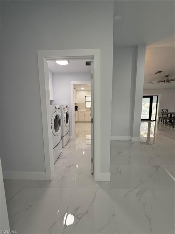 Laundry area with light marble finish floors and washing machine and dryer