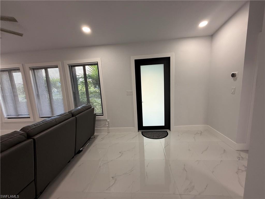 Living room featuring recessed lighting, light marble finish flooring, and a ceiling fan