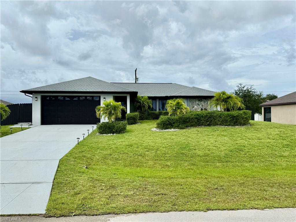 Ranch-style house featuring a garage, concrete driveway, a front yard, and a shingled roof