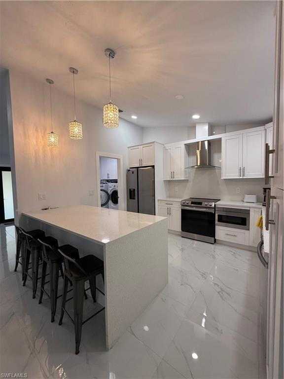 Kitchen featuring a breakfast bar area, white cabinets, stove, pendant lighting, and a peninsula