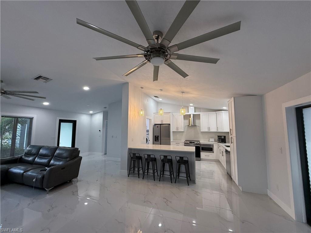 Living area featuring ceiling fan, lofted ceiling, recessed lighting, and light marble finish floors