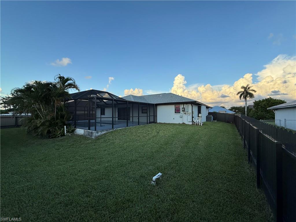 Rear view of property featuring a fenced backyard, a lanai, and a sunroom