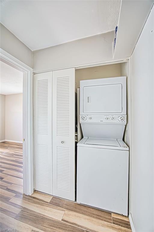 Laundry area with light wood-style flooring and stacked washer and dryer