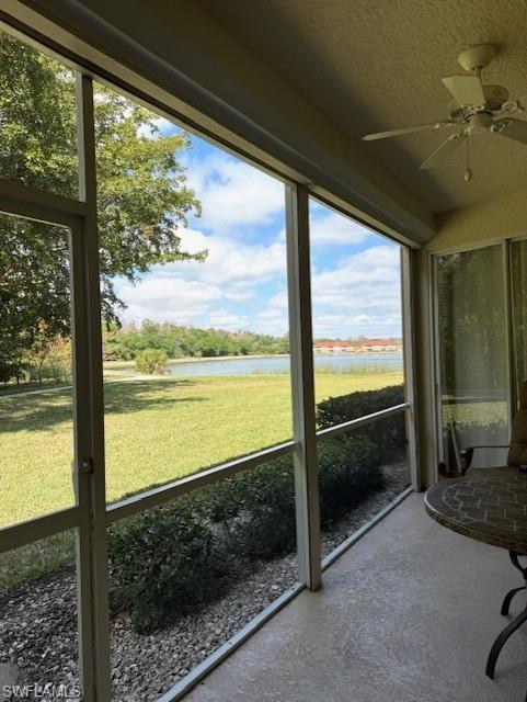 Unfurnished sunroom with ceiling fan and a water view