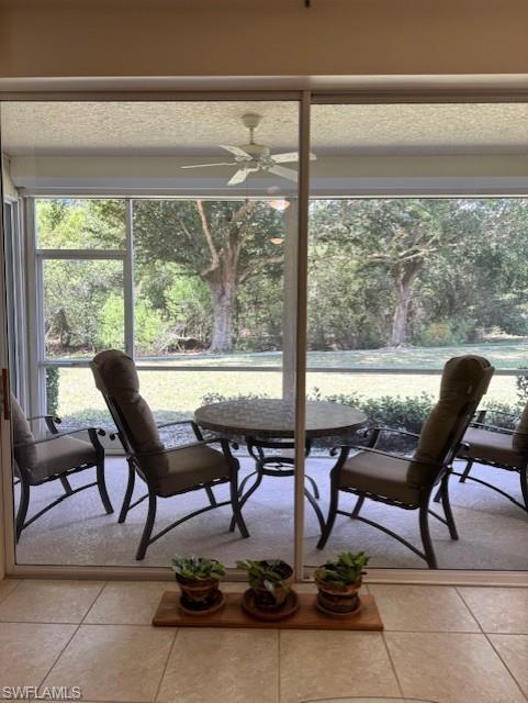 Dining area featuring ceiling fan, light tile patterned flooring, and view of scattered trees