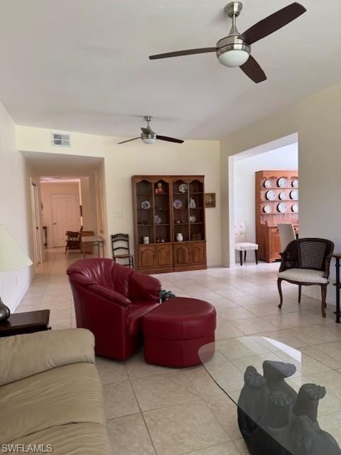 Living area featuring a ceiling fan and light tile patterned flooring