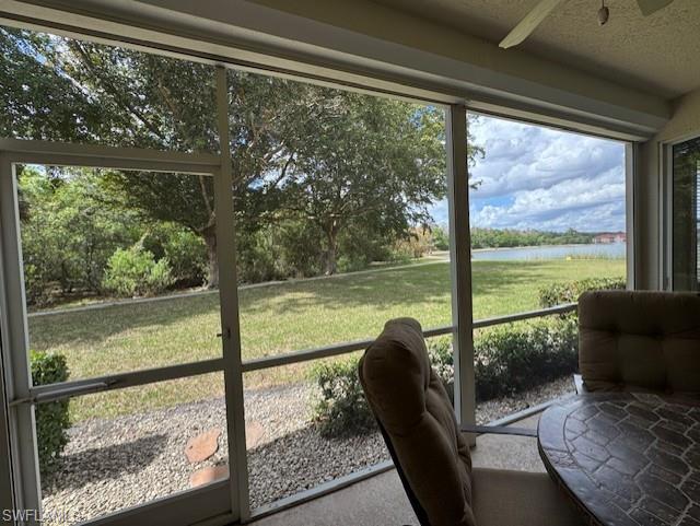 Sunroom with a water view and a ceiling fan