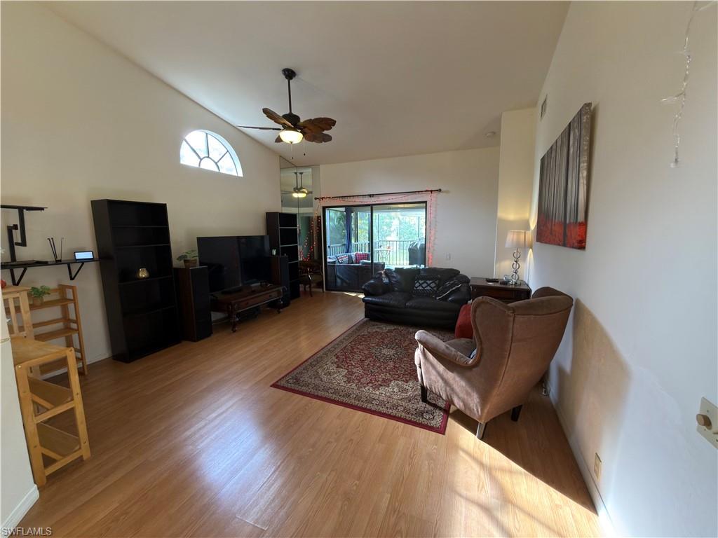 Living room with wood finished floors, a ceiling fan, and vaulted ceiling