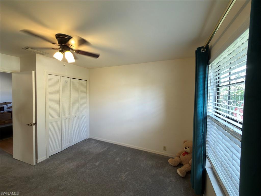 Unfurnished bedroom featuring dark carpet, a ceiling fan, and a closet